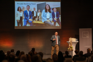 Steaker Larry Hagman im Hintergrund eine Präsentation mit unserem PB Team