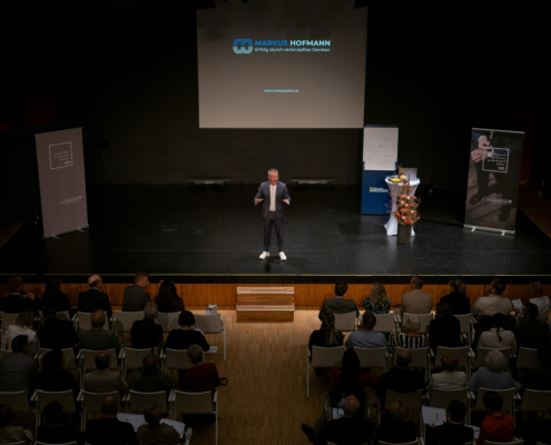 Foto vom Redner Markus Hofmann auf der Bühne des Gemeindezentrums Schöffl